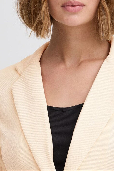 Portrait of a model wearing the ICHI KATE ivory corduroy blazer over a black top, showing the collar and shoulders.