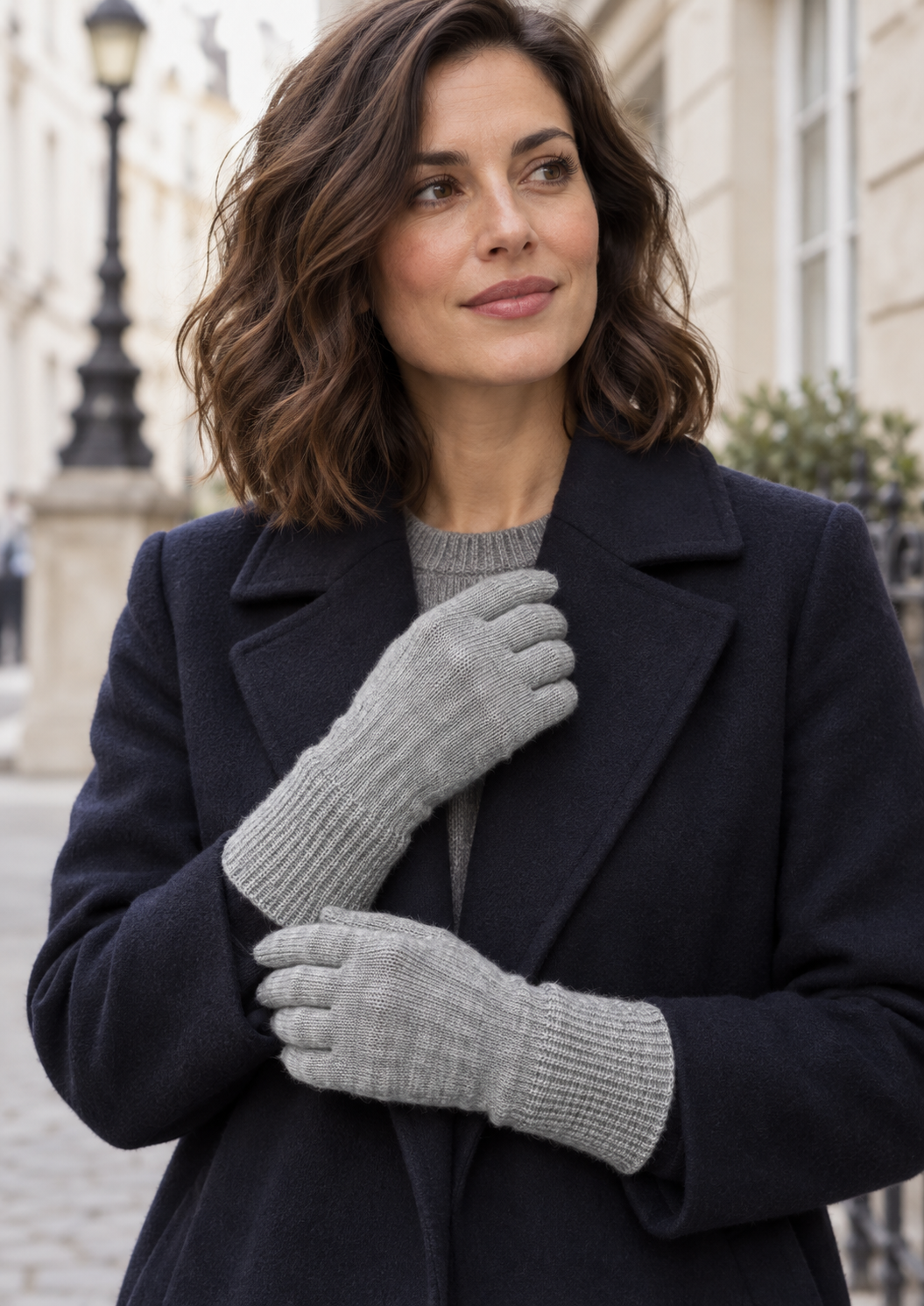 Model wearing light grey s.Oliver gloves with a navy coat on a city street